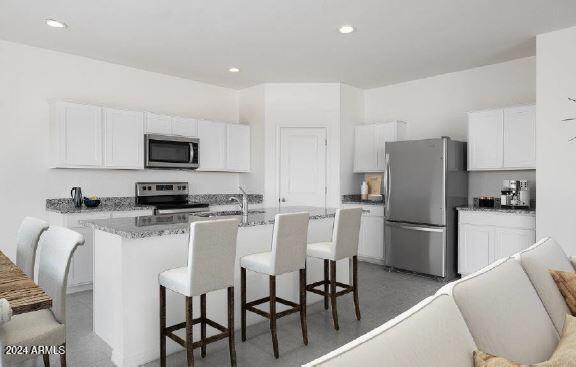 kitchen with a center island with sink, white cabinets, a breakfast bar area, and appliances with stainless steel finishes