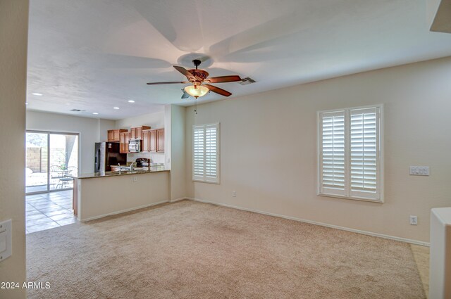 unfurnished living room with light carpet and ceiling fan