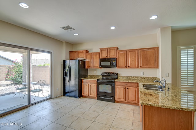 kitchen featuring sink, light stone countertops, black appliances, and a healthy amount of sunlight