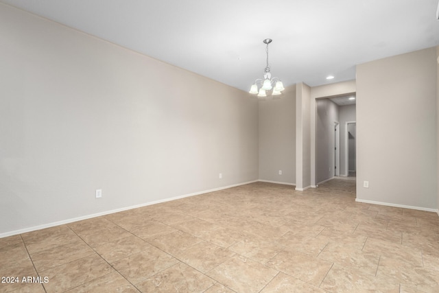 unfurnished room featuring a chandelier