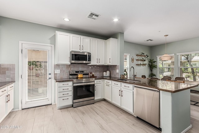 3037 E Hobart St, Gilbert, AZ 85296 - kitchen featuring stainless steel appliances, dark countertops, a peninsula, tasteful backsplash, and white cabinetry