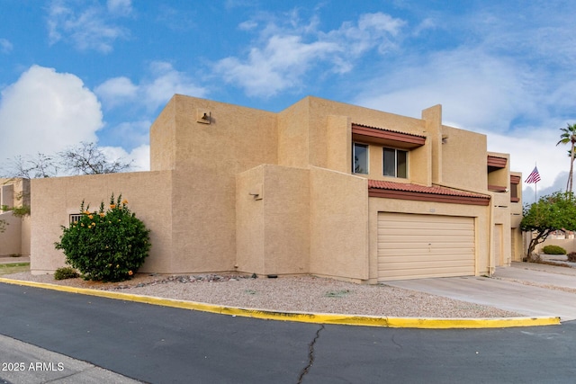 adobe home featuring driveway, an attached garage, and stucco siding