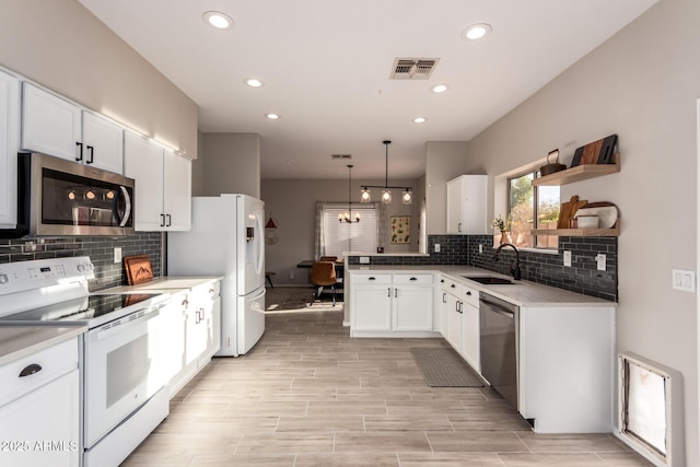 kitchen with appliances with stainless steel finishes, tasteful backsplash, hanging light fixtures, white cabinets, and sink