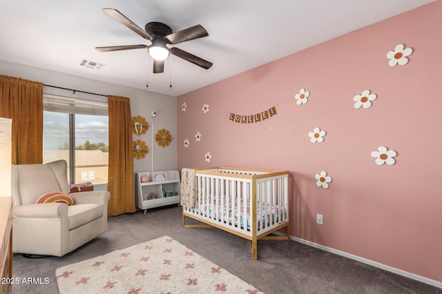 carpeted bedroom with ceiling fan and a crib