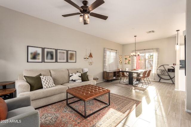 living room with ceiling fan with notable chandelier and light hardwood / wood-style flooring