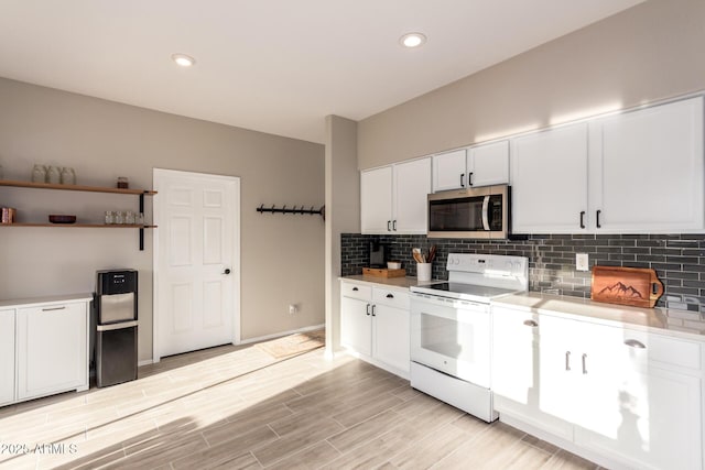 kitchen with white cabinets, white electric range oven, and tasteful backsplash