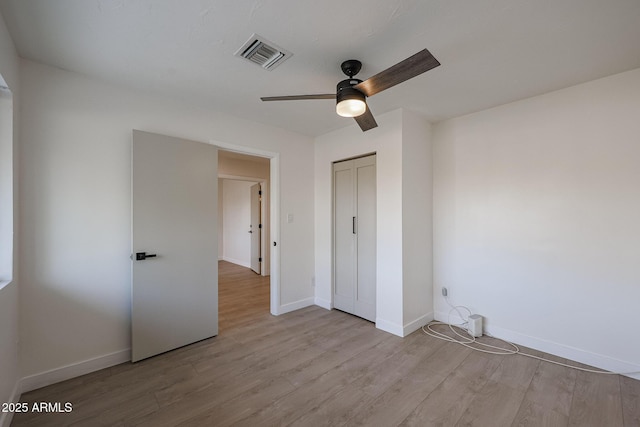 unfurnished bedroom featuring ceiling fan, light hardwood / wood-style floors, and a closet