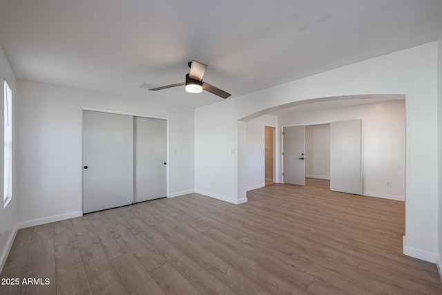 unfurnished bedroom featuring ceiling fan, light hardwood / wood-style floors, and a closet