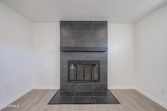 details with a tile fireplace, hardwood / wood-style floors, and a textured ceiling