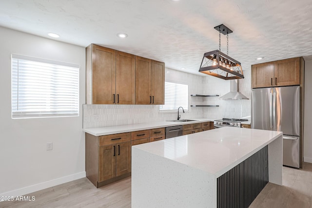 kitchen featuring sink, a center island, wall chimney range hood, pendant lighting, and appliances with stainless steel finishes