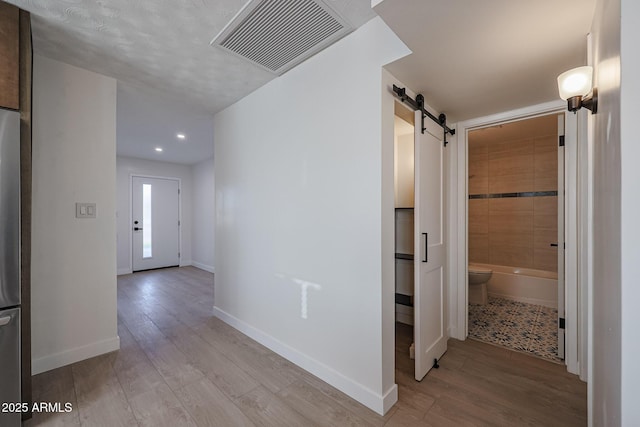 hall featuring a barn door and light hardwood / wood-style floors