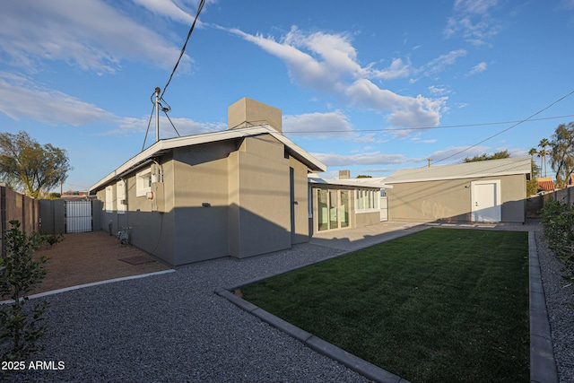 view of property exterior with a lawn, an outdoor structure, and a patio