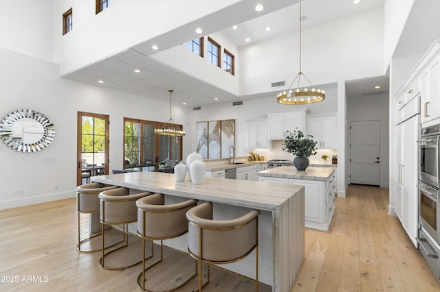 kitchen with a spacious island, an inviting chandelier, a kitchen bar, and light stone countertops