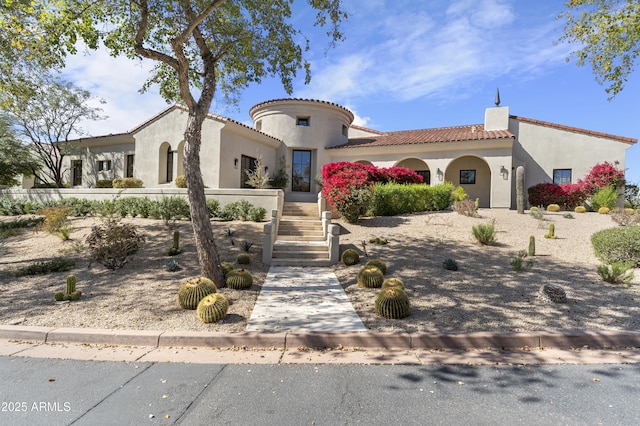 mediterranean / spanish house featuring a tile roof, fence, and stucco siding