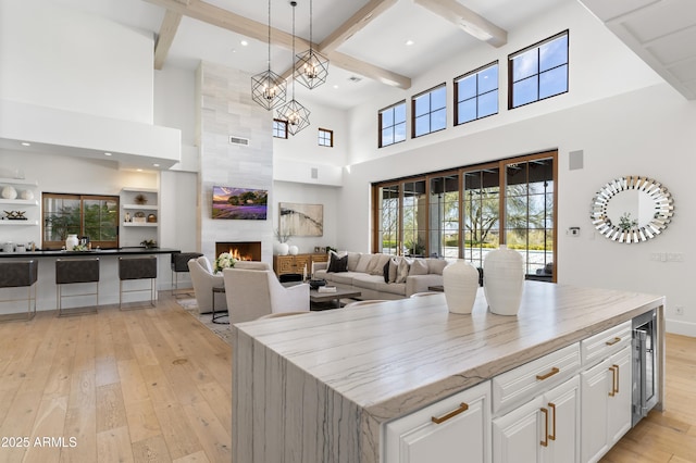 kitchen with a center island, decorative light fixtures, light wood-style flooring, open floor plan, and white cabinets