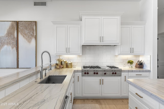 kitchen with white cabinetry, stainless steel gas cooktop, visible vents, and a sink