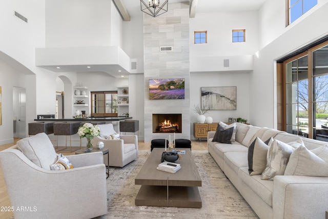 living room with beamed ceiling, a fireplace, visible vents, and baseboards