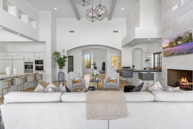 living area with visible vents, arched walkways, and a tile fireplace