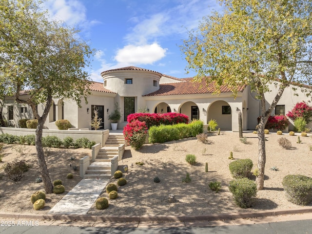 mediterranean / spanish-style home featuring a tile roof, stairs, and stucco siding