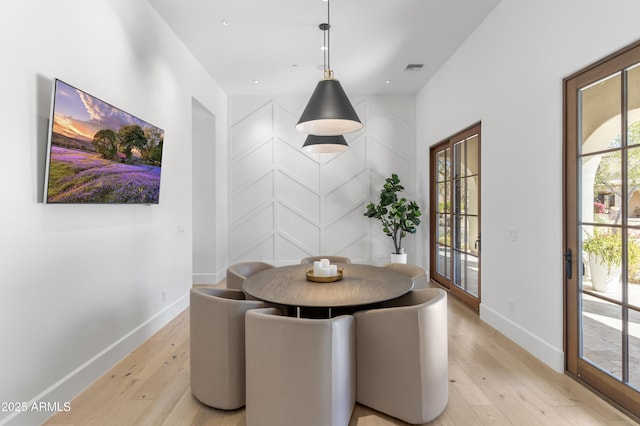 dining room with light wood-style flooring, visible vents, and baseboards