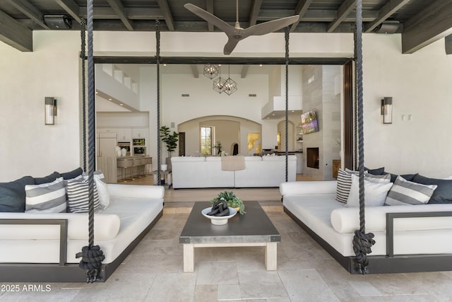 living area featuring arched walkways, beamed ceiling, and a towering ceiling