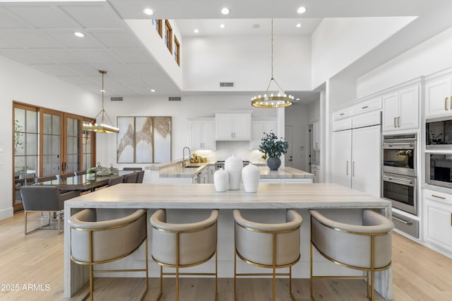 kitchen with hanging light fixtures, a breakfast bar, white cabinetry, and a notable chandelier