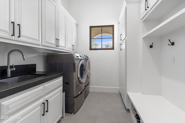 clothes washing area featuring light tile patterned floors, washing machine and dryer, a sink, baseboards, and cabinet space