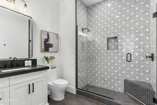 full bathroom featuring toilet, tiled shower, tile patterned flooring, and vanity