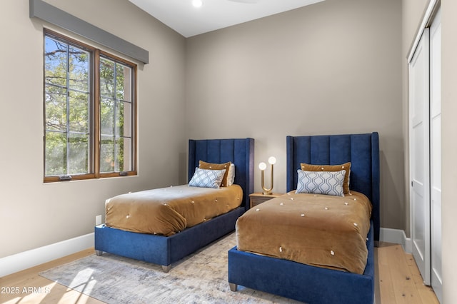 bedroom with a closet, baseboards, and wood finished floors