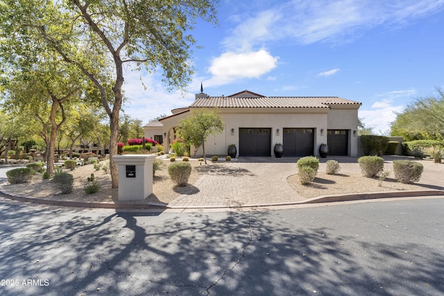 mediterranean / spanish-style house with a garage, driveway, a tiled roof, and stucco siding