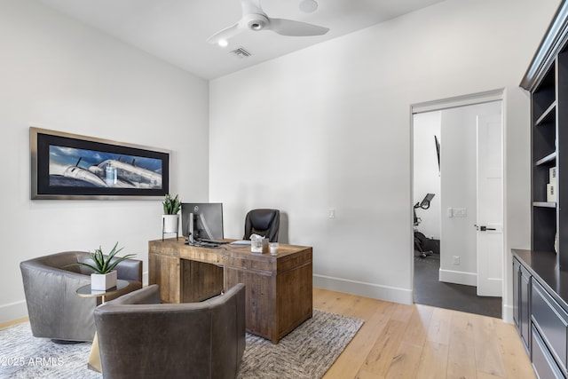 home office with visible vents, ceiling fan, light wood-style flooring, and baseboards