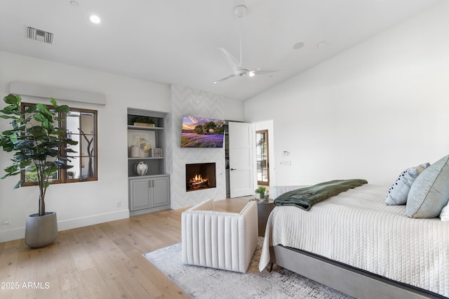 bedroom featuring lofted ceiling, recessed lighting, a fireplace, visible vents, and light wood finished floors