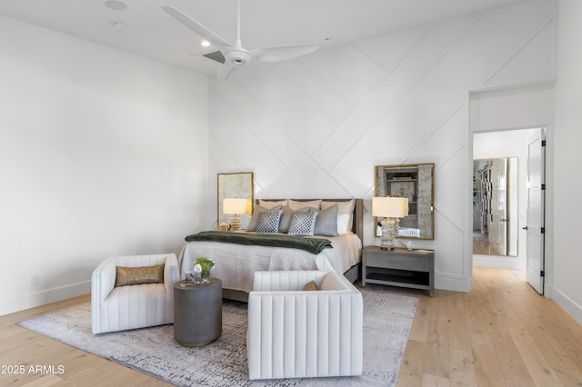 bedroom with a towering ceiling, light wood-style floors, baseboards, and a ceiling fan