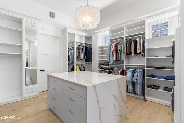 walk in closet with a notable chandelier and light wood-style floors