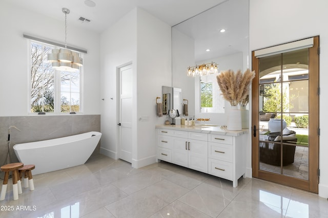 bathroom featuring recessed lighting, visible vents, a freestanding bath, and vanity