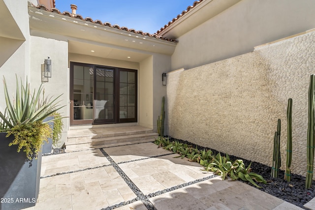 doorway to property featuring a patio, a tiled roof, and stucco siding