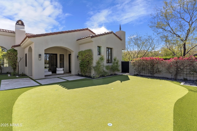 rear view of house featuring a patio area, fence, and stucco siding