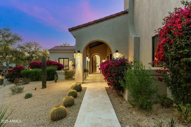 doorway to property with a tiled roof and stucco siding