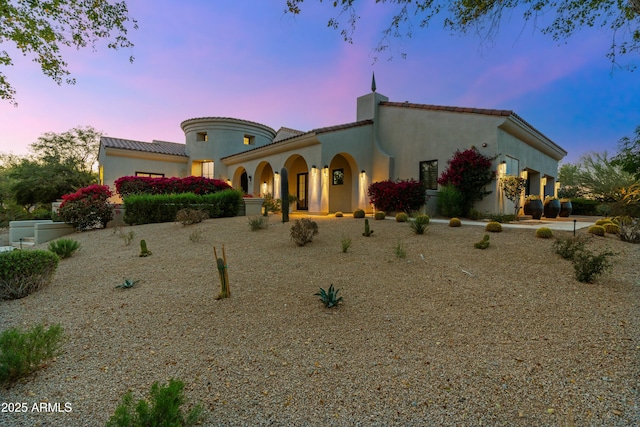 mediterranean / spanish house featuring a tiled roof and stucco siding