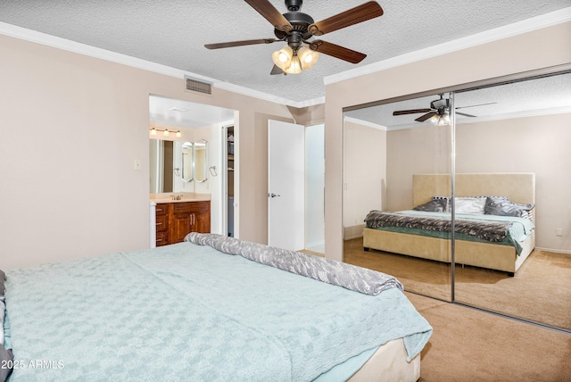 bedroom featuring crown molding, ceiling fan, a textured ceiling, light carpet, and a closet