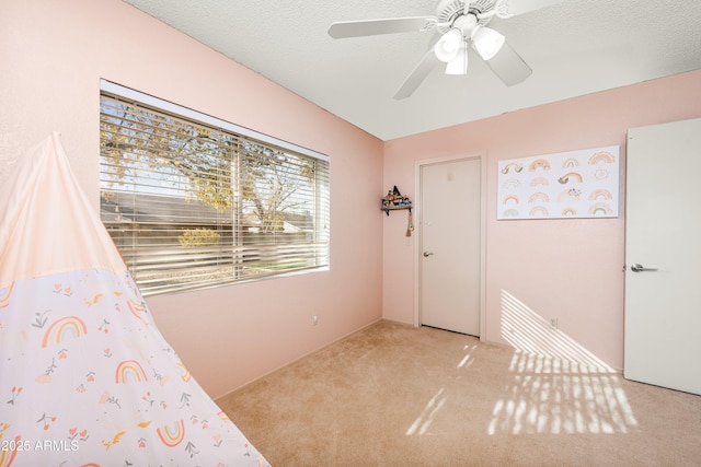 interior space featuring ceiling fan, light carpet, and a textured ceiling