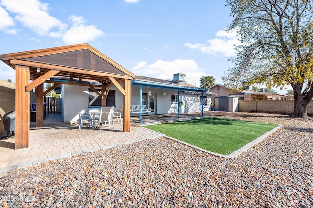 back of property with a patio, a yard, and a storage shed