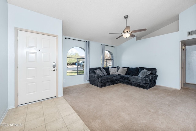 living room with ceiling fan, light colored carpet, vaulted ceiling, and a textured ceiling