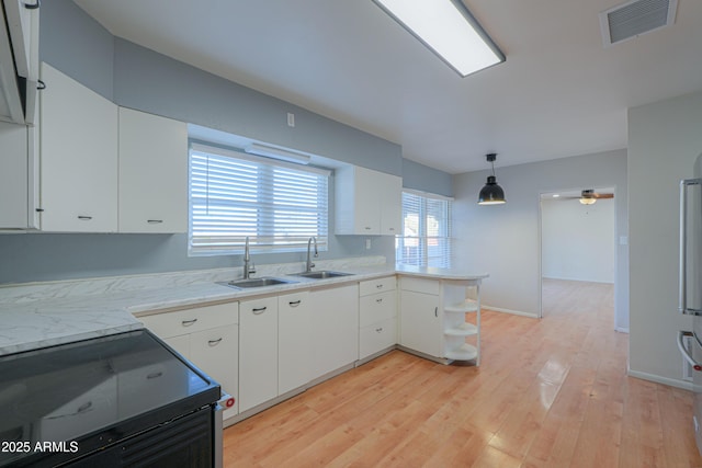 kitchen with pendant lighting, black electric range oven, white cabinets, and sink