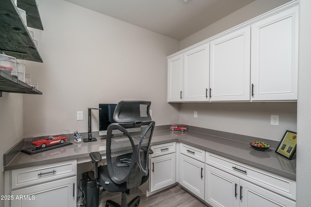 office with light wood-style floors and built in desk