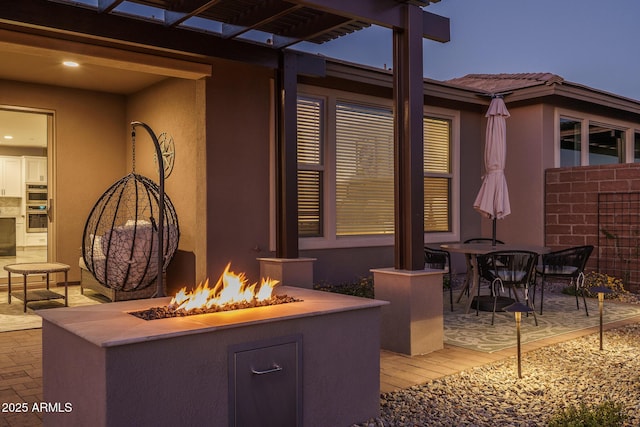 patio terrace at dusk featuring a fire pit and outdoor dining space