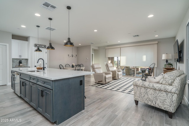 kitchen featuring white cabinets, open floor plan, a sink, and an island with sink