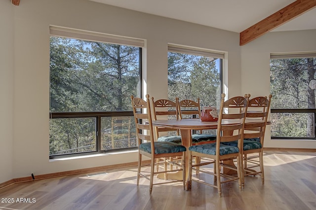 dining area featuring wood finished floors, beam ceiling, and baseboards