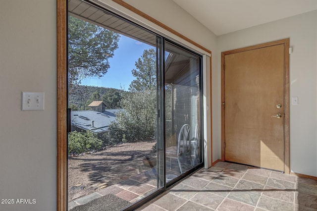 doorway featuring baseboards and stone tile floors