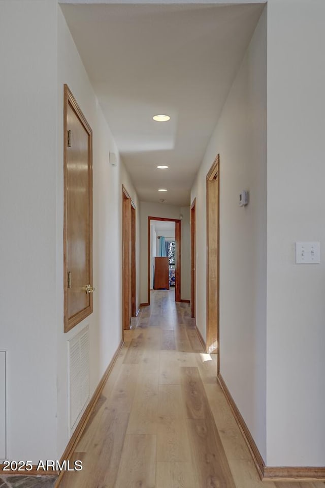 hall featuring light wood-type flooring, visible vents, baseboards, and recessed lighting